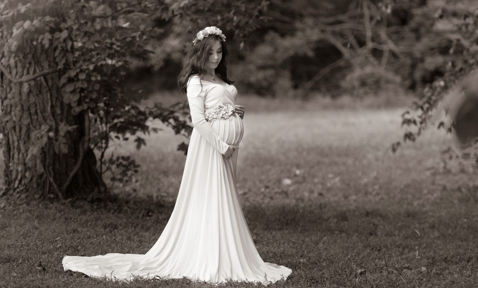 A woman in a long, loose dress standing outdoors in soft daylight.