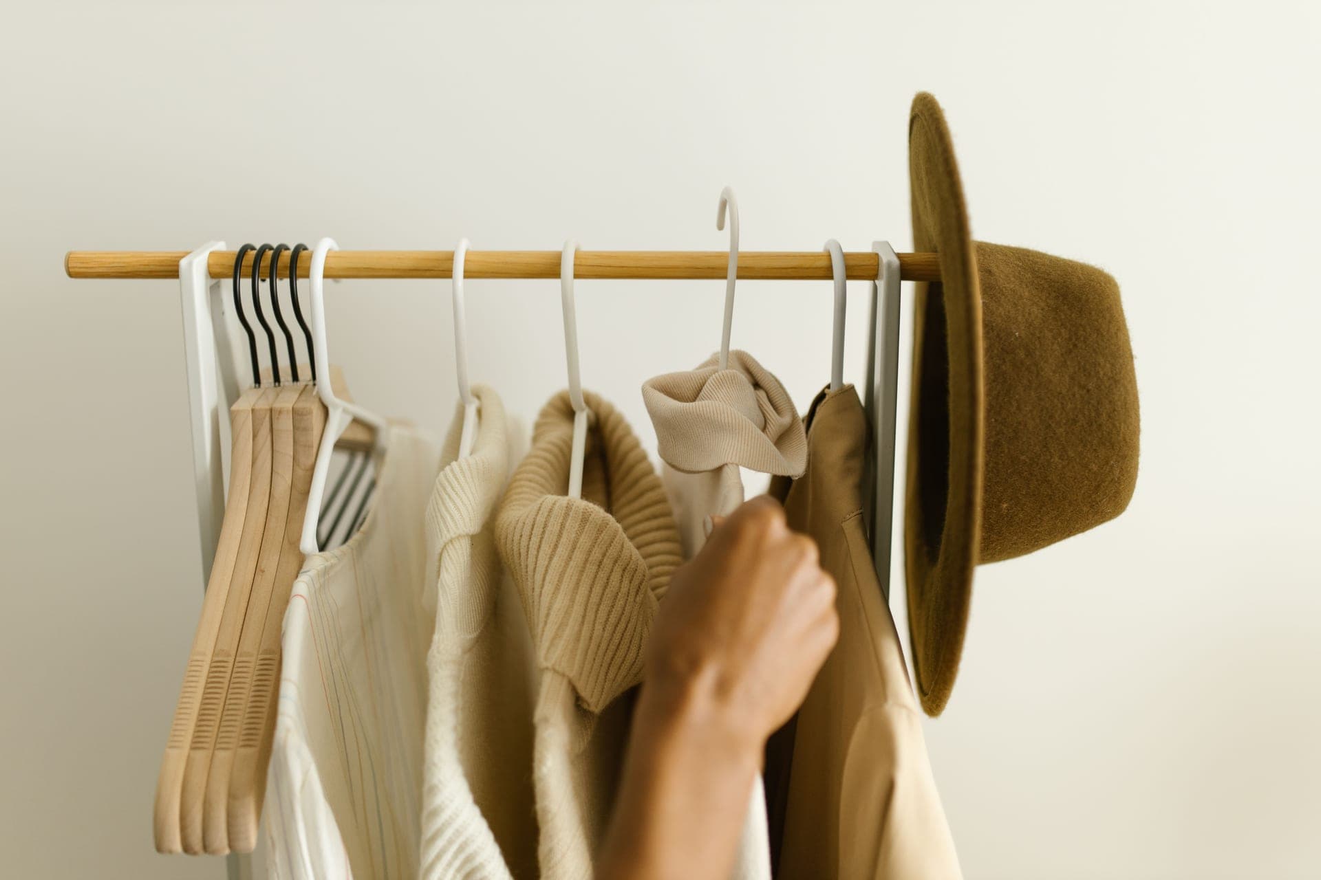 A rail of neutral-toned clothes in a minimal room.