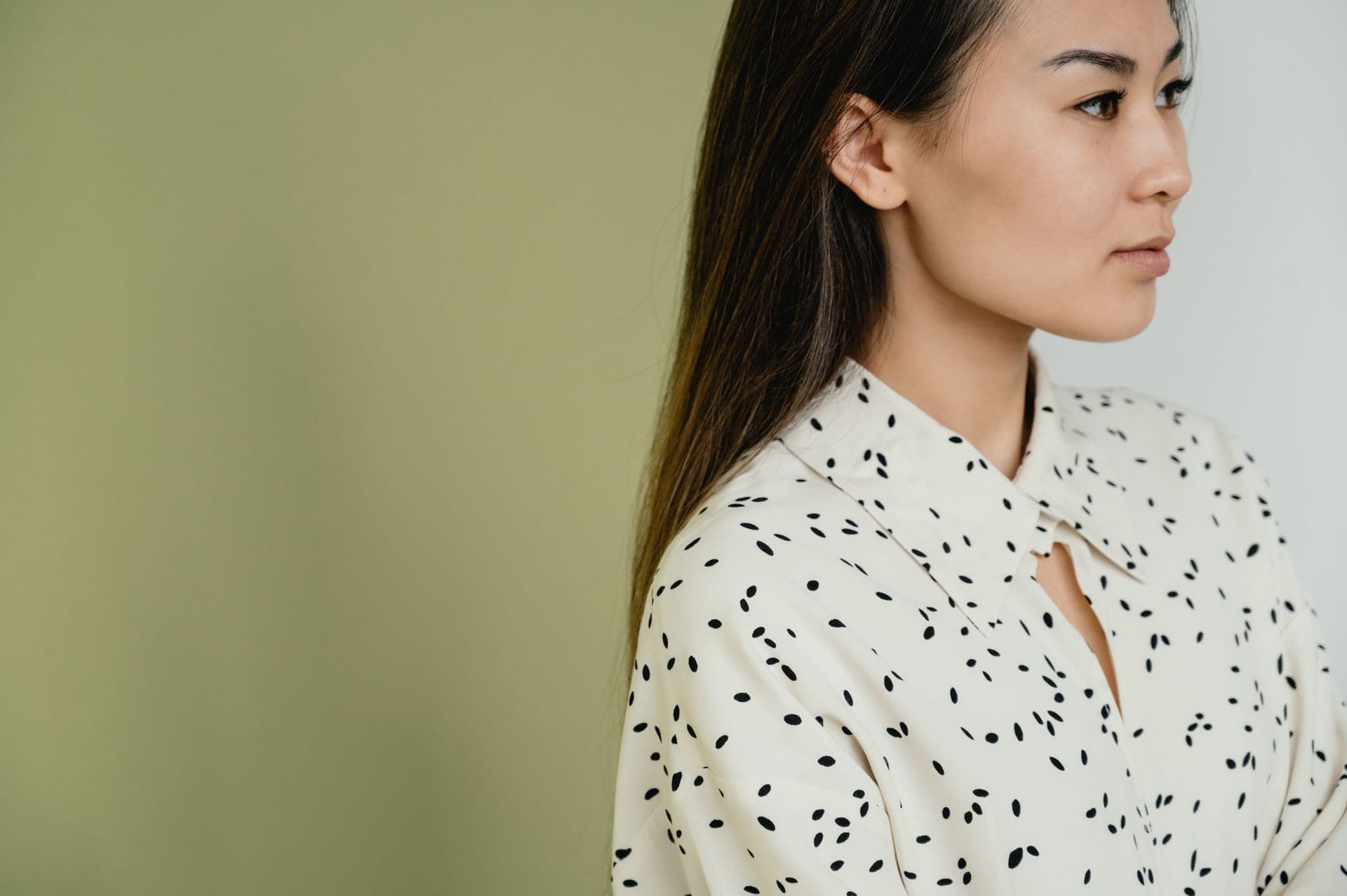 A person in a loose blouse standing against a neutral background.