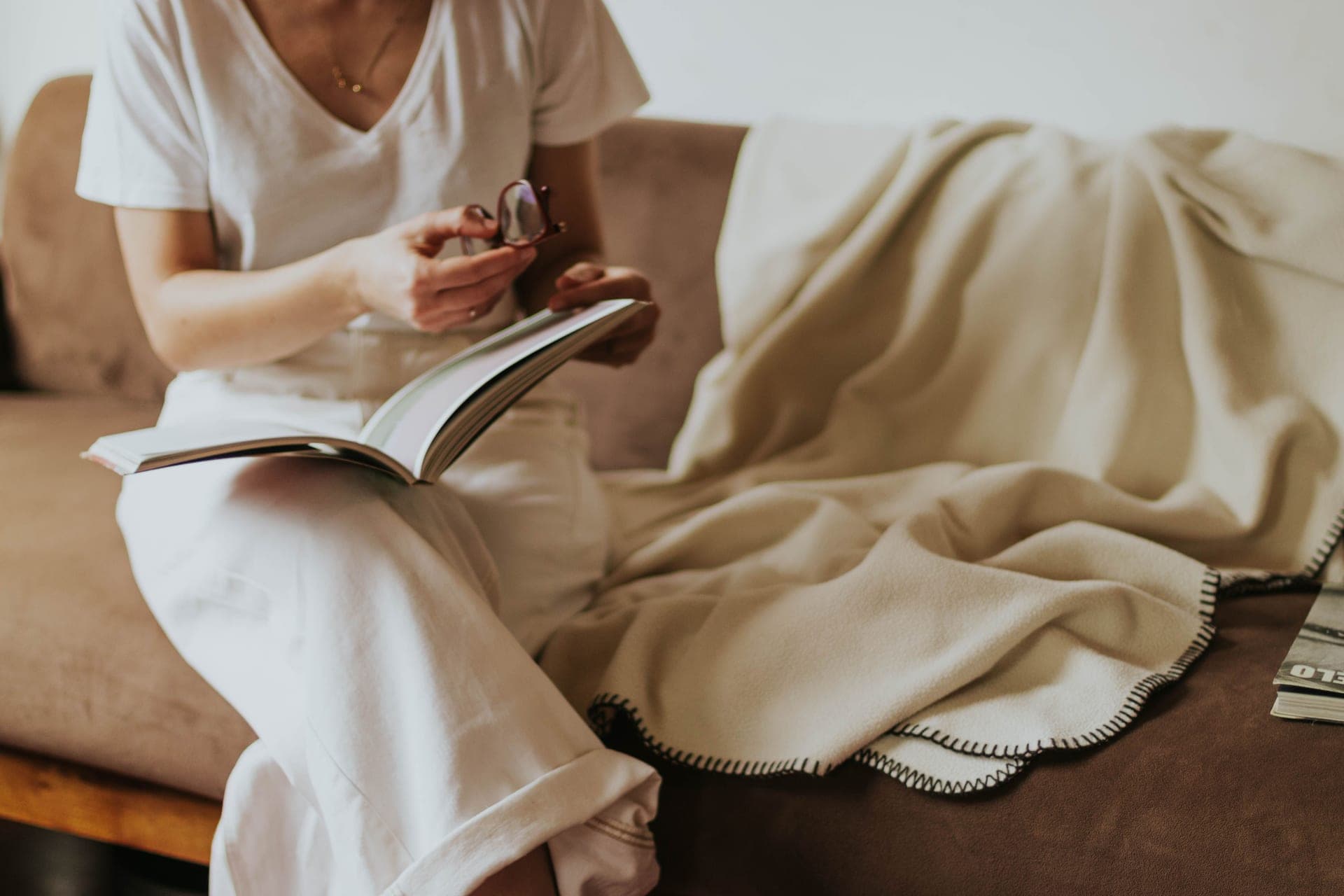 A person resting on a bed beside a newborn in a calm, neutral bedroom.