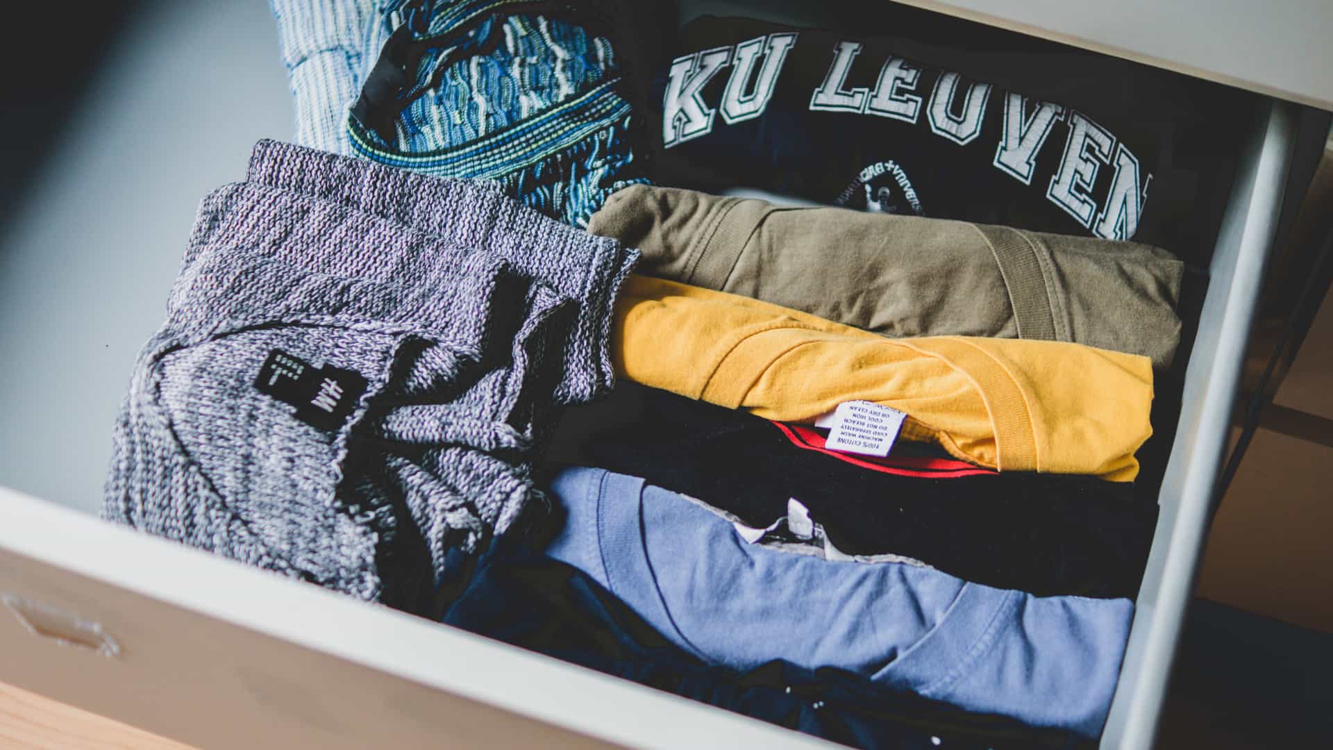 A stack of folded clothes inside an open drawer.