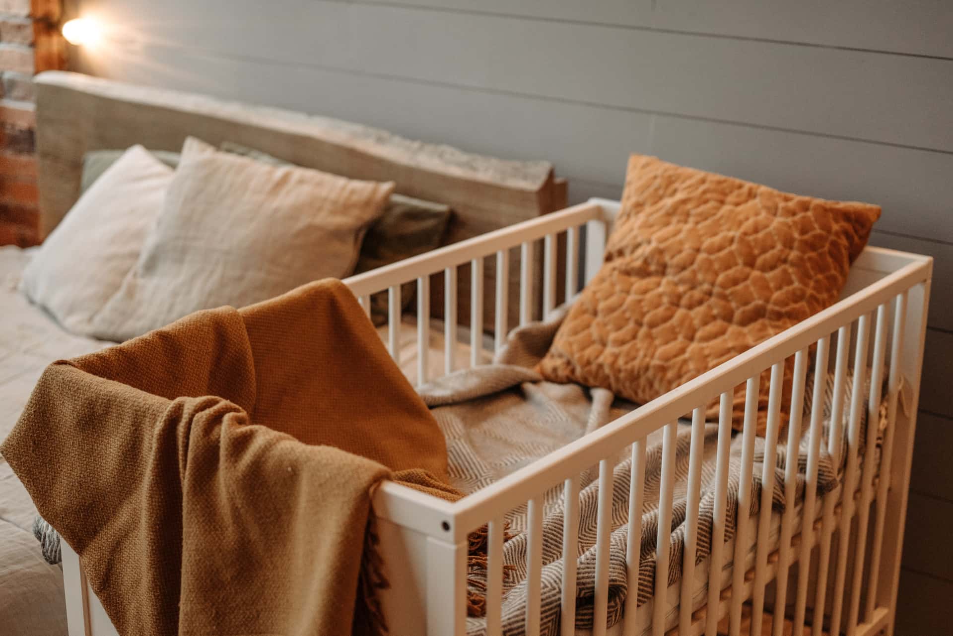 A cushion and blanket on an armchair in a neutral nursery.