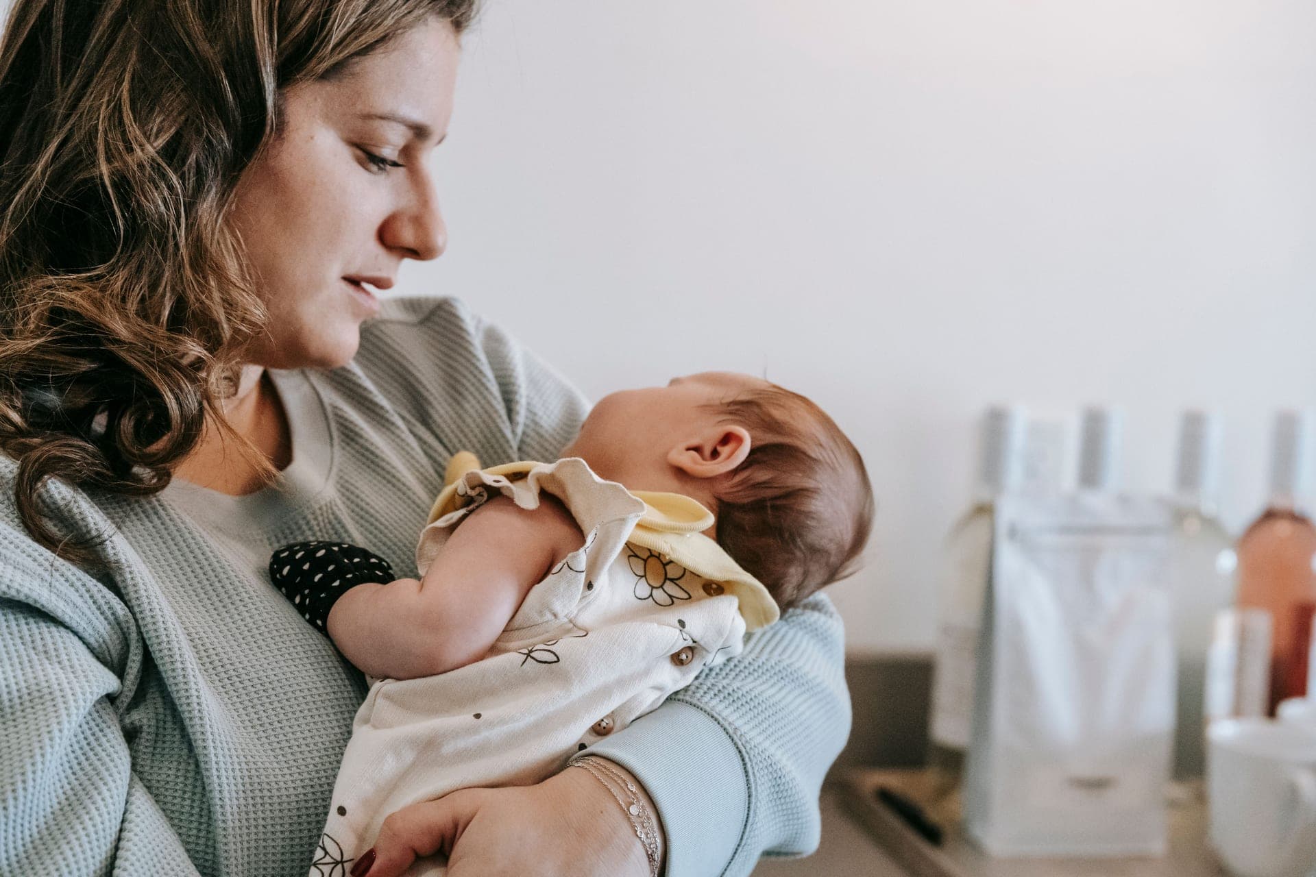 A parent holding a newborn against their chest at home.