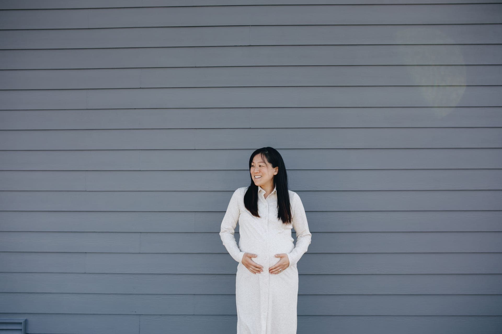 A pregnant person standing against a neutral background.