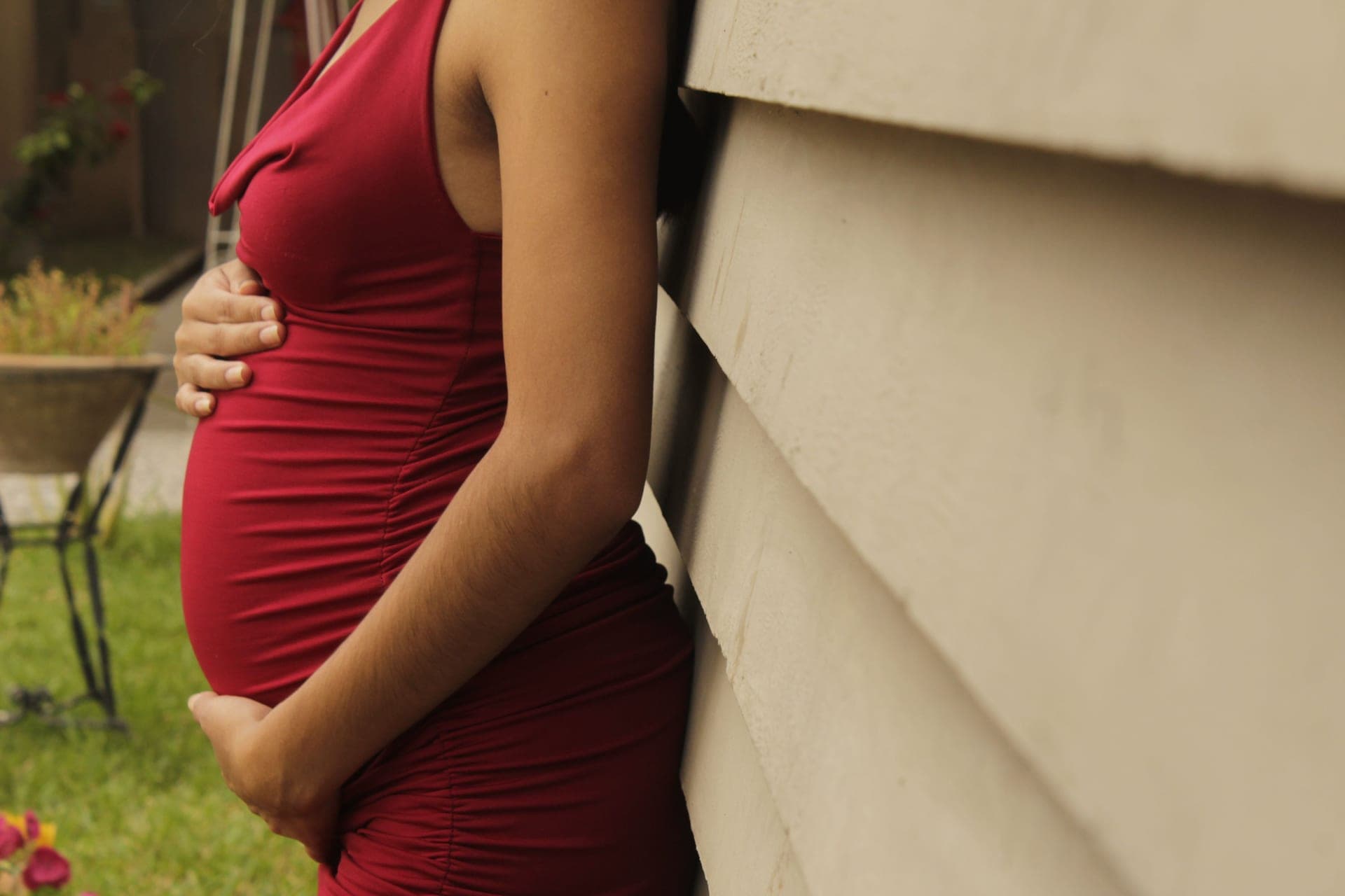 A pregnant person resting a hand on the side of their belly.