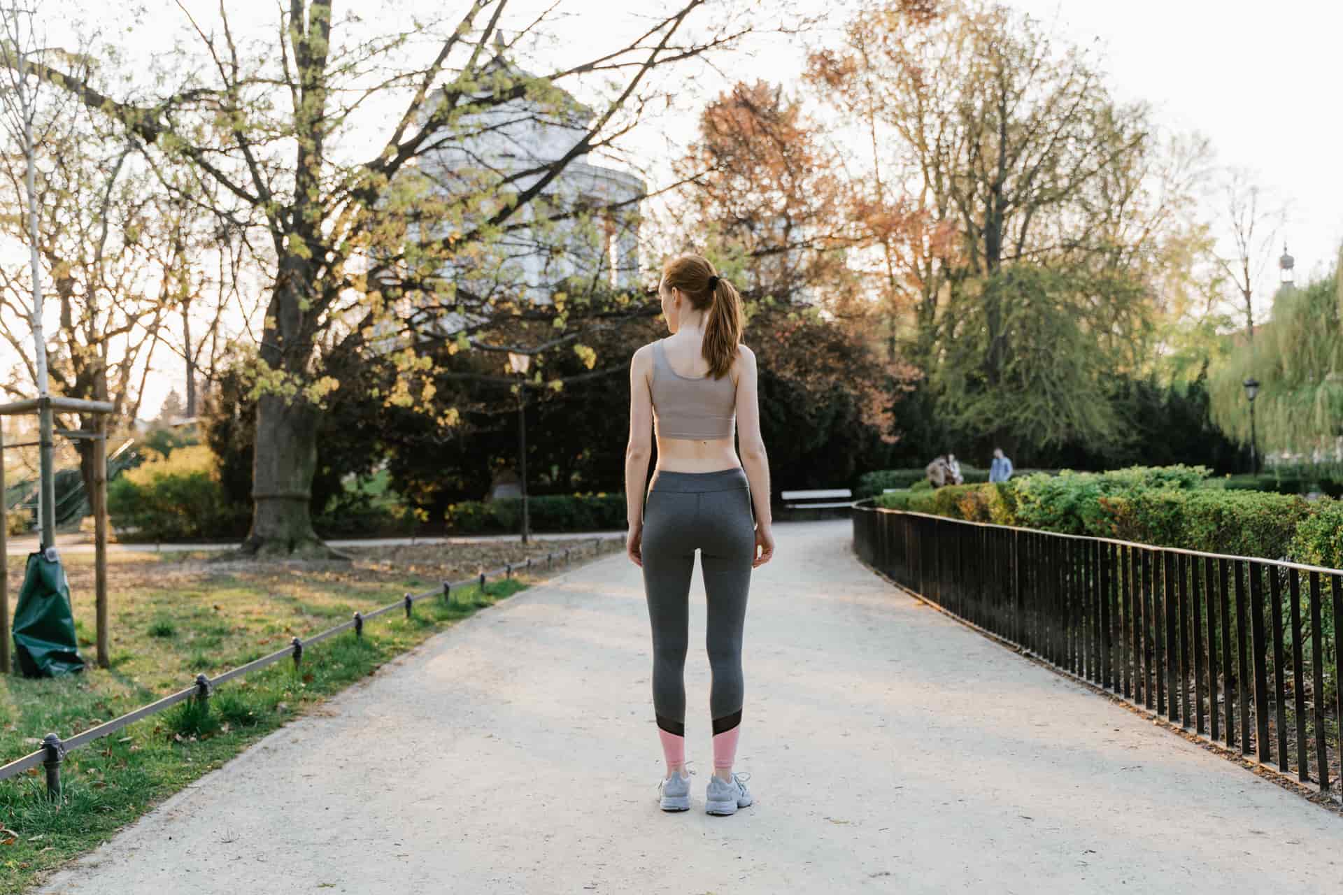 A person walking outdoors in activewear along a path.