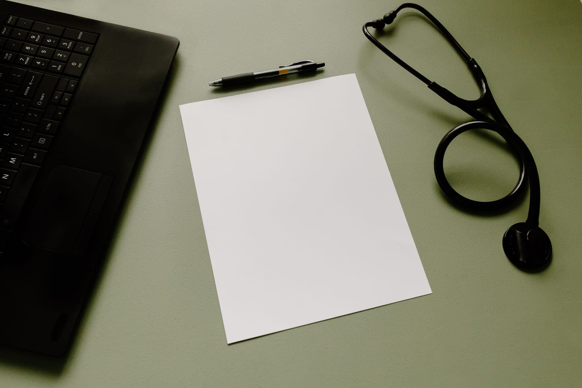 A stethoscope resting on a plain desk in a calm clinical setting.