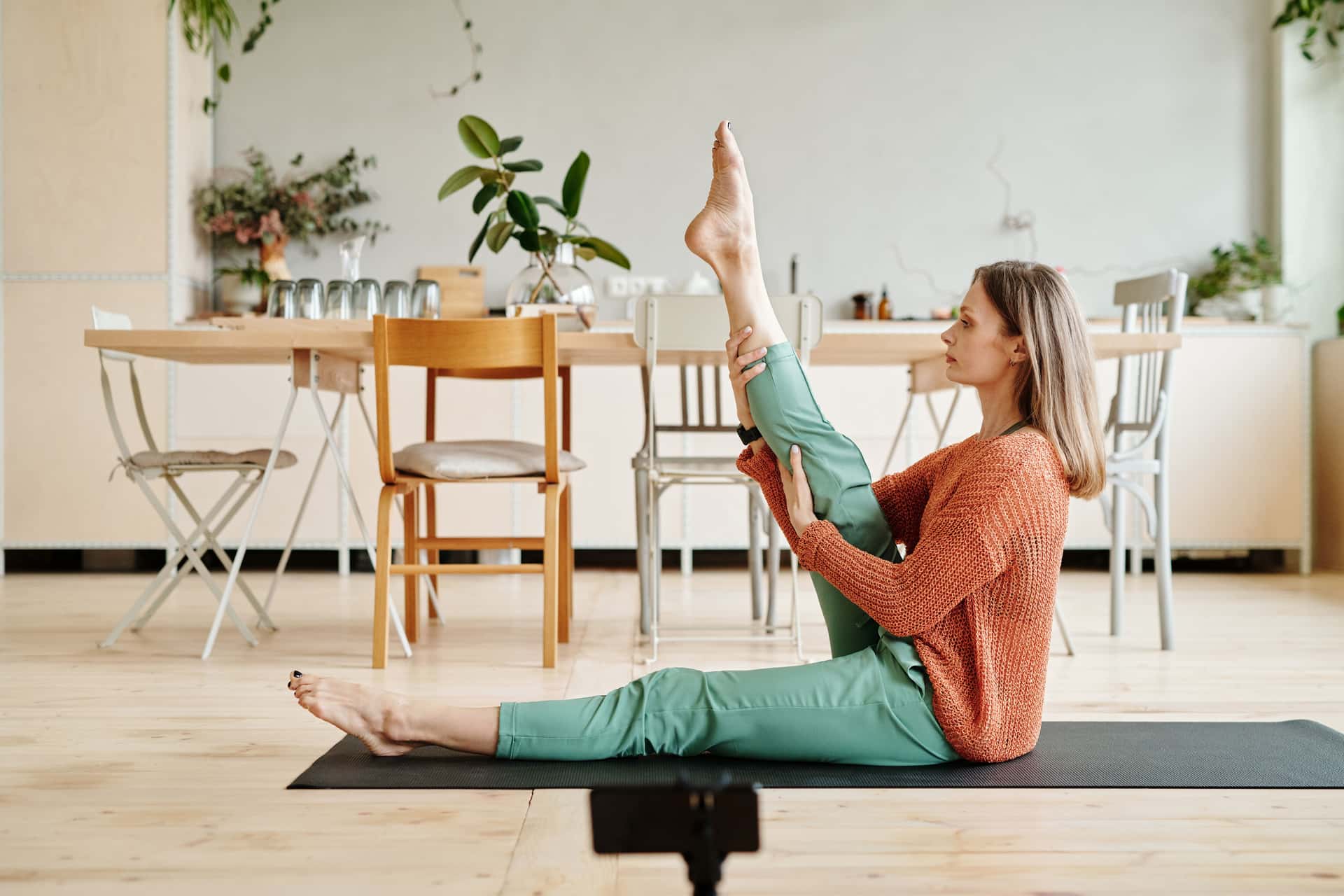 A person stretching one leg while seated on a yoga mat.