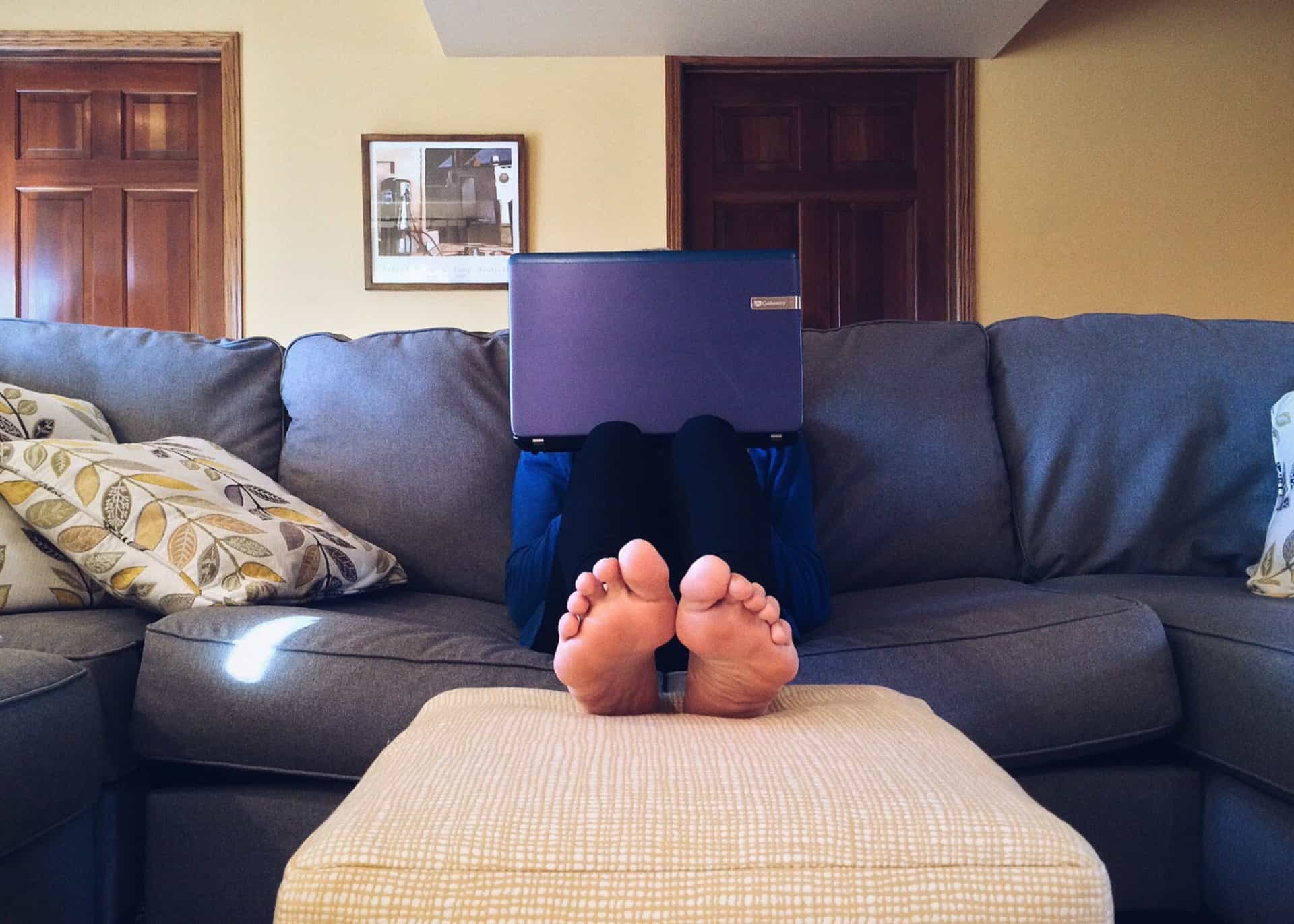 Bare feet raised on a cushion on a sofa.