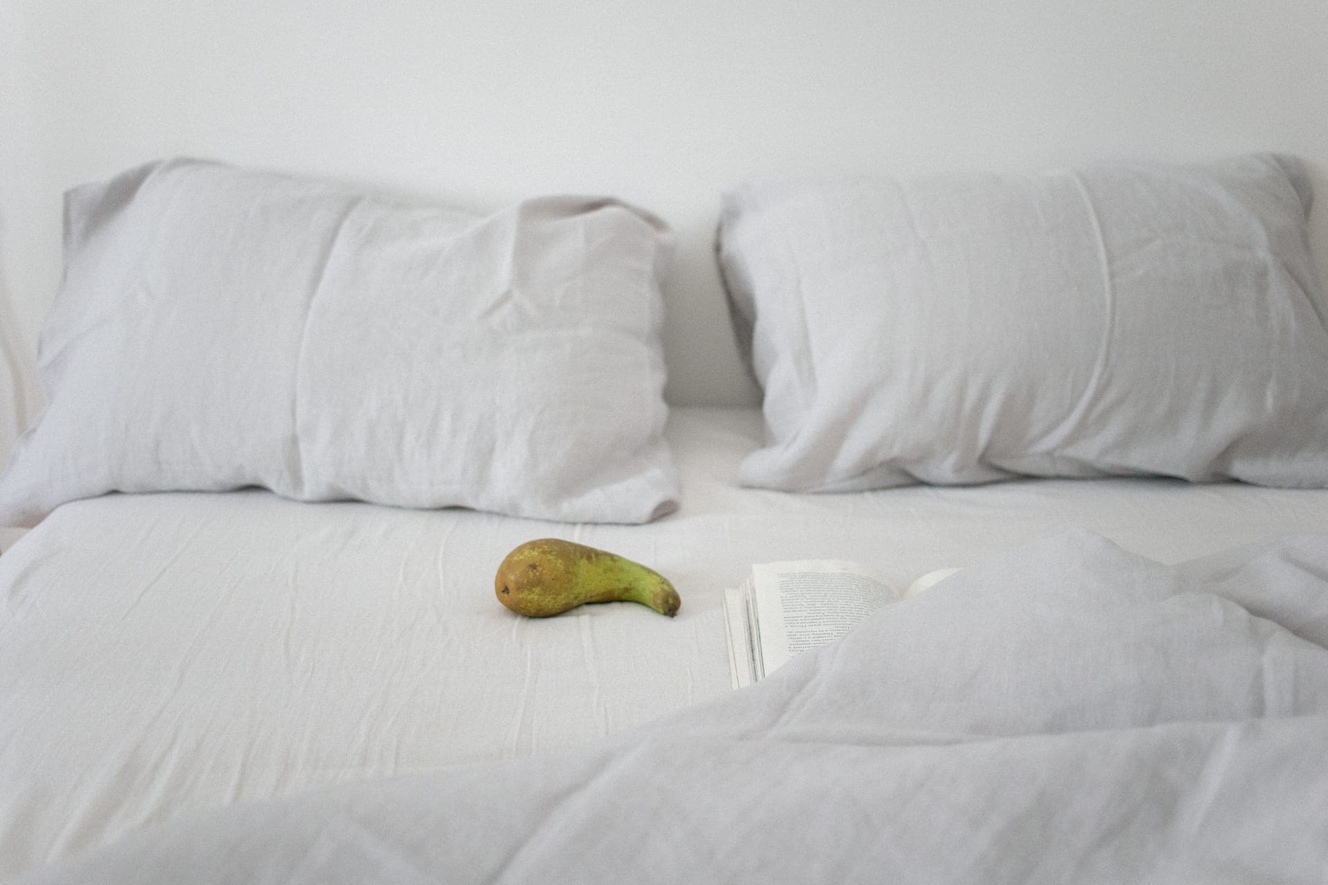 A neatly made bed with a white duvet in daylight.
