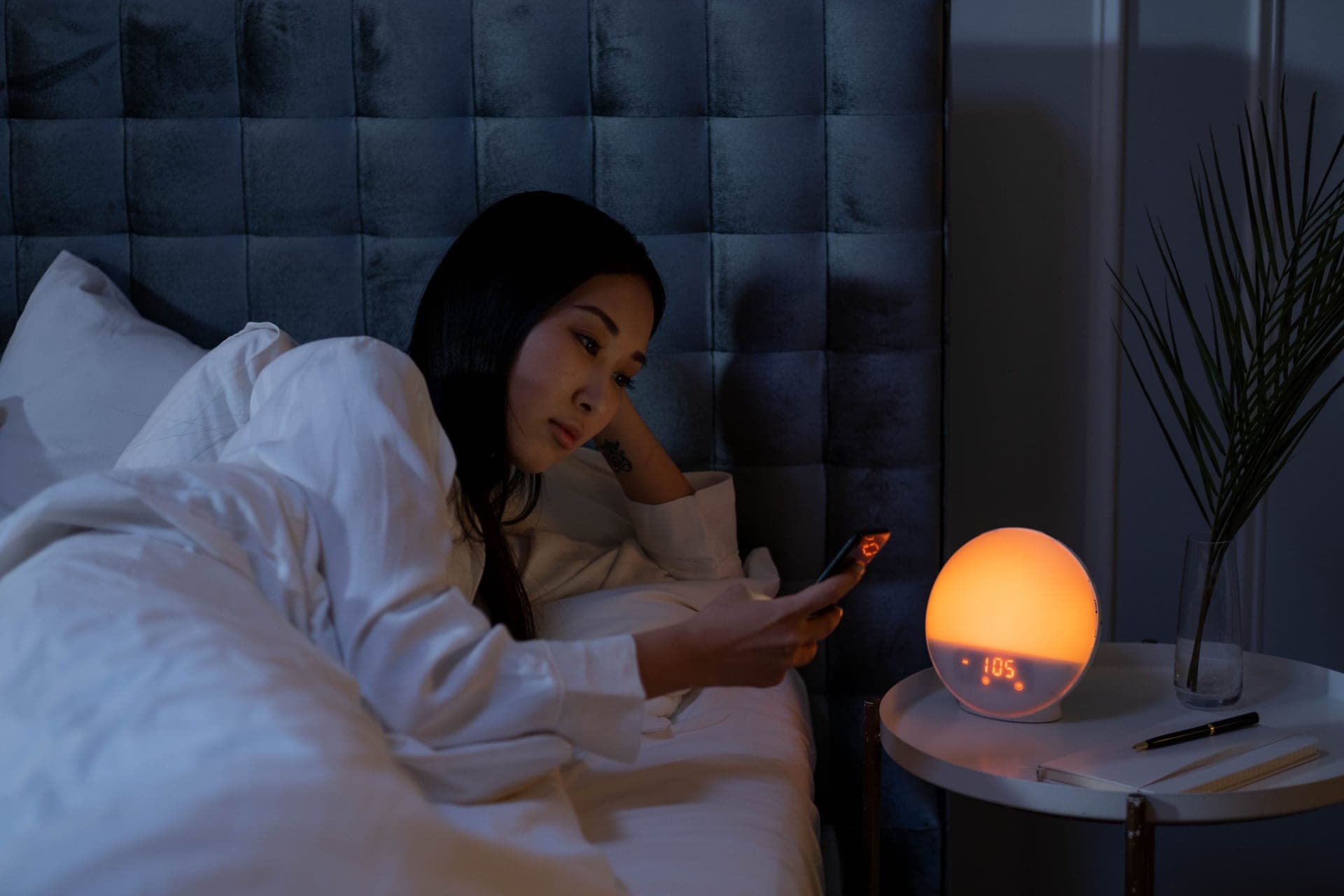 A person awake in bed at night with a bedside lamp on.