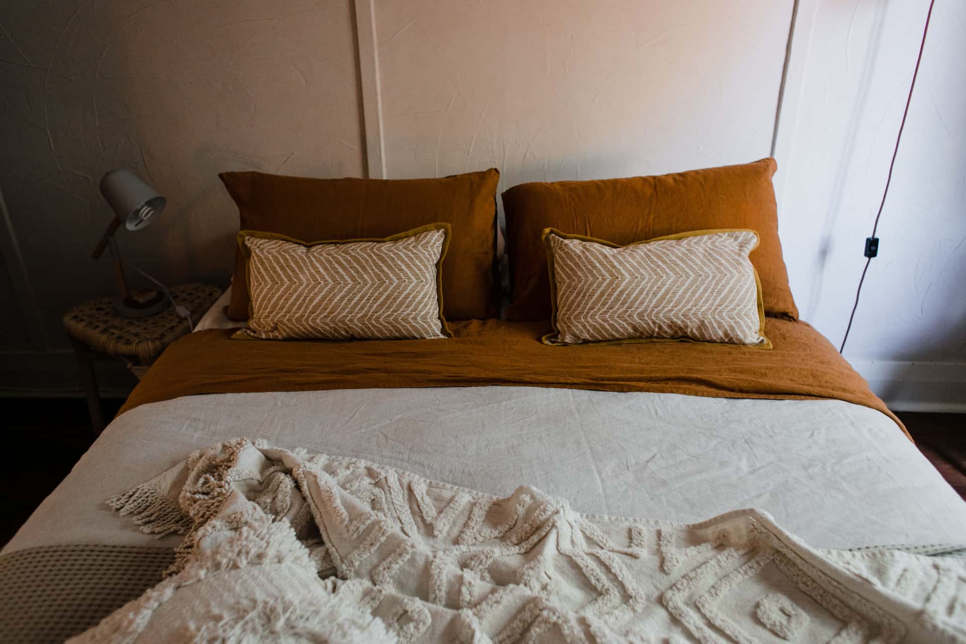Pillows arranged on a made bed in a neutral bedroom.