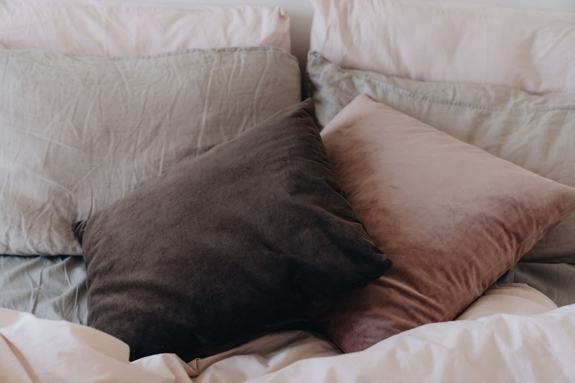 A large body pillow laid across neutral linen bedding.
