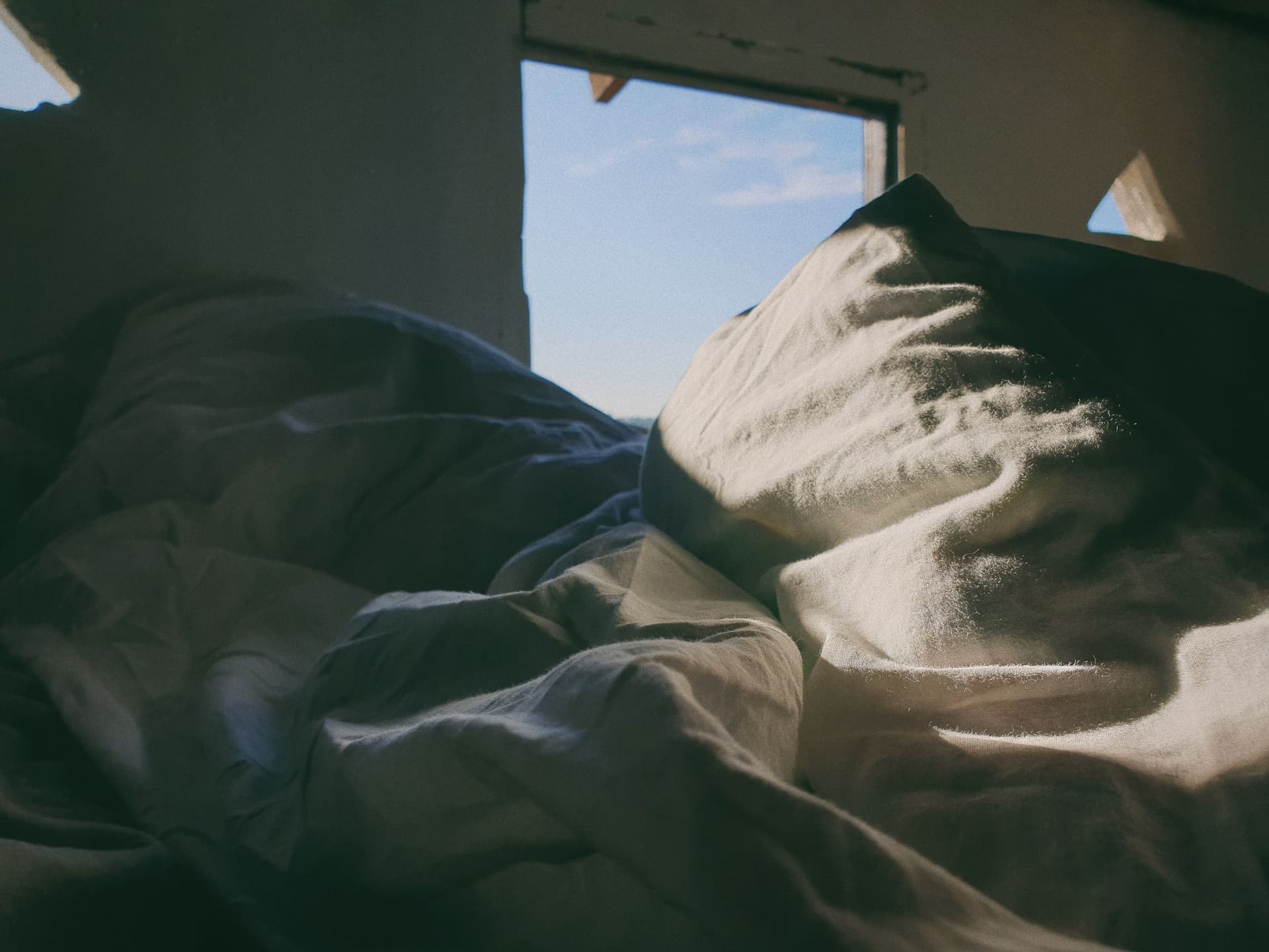 Rumpled white bedsheets catching morning light.