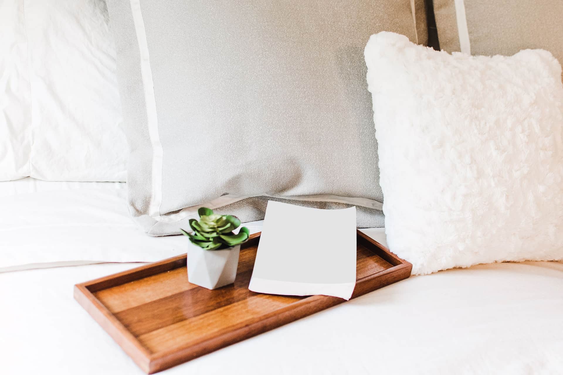 A small cushion resting on white bedsheets.