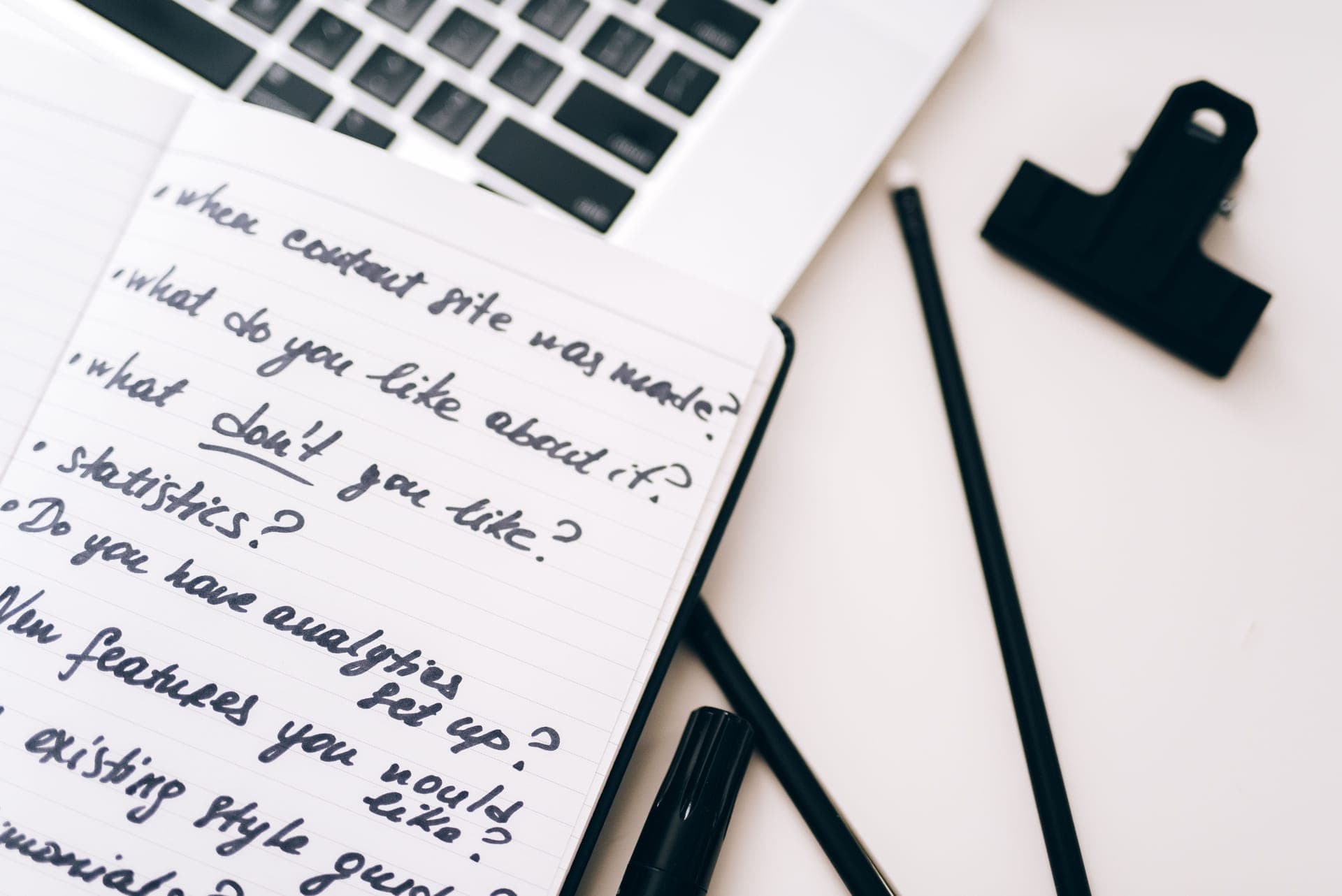 An open notebook with handwritten notes and a pen on a desk.